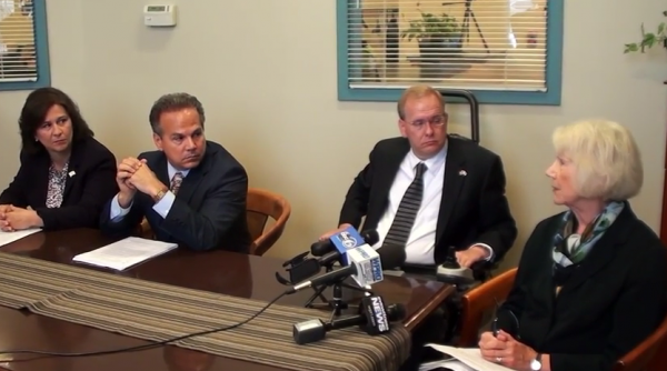 Secretary of State Nellie Gorbea and congressmen David Cicilline and Jim Langevin listen to voting rights activist Jane Koster.
