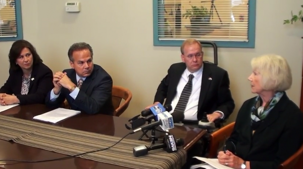 Secretary of State Nellie Gorbea and congressmen David Cicilline and Jim Langevin listen to voting rights activist Jane Koster. 